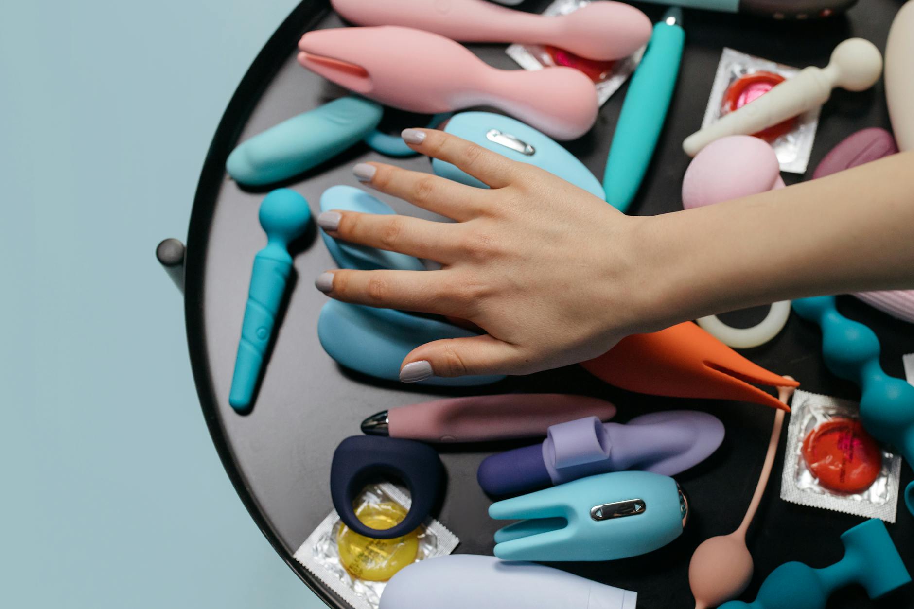 A blue silicone lemon clitoral vibrator held in hand against a solid purple background
