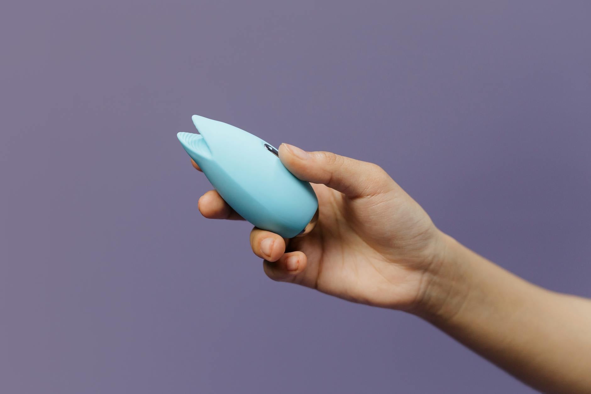 A silicone clitoral vibrator held in hand, symbolizing self-care during medication transitions